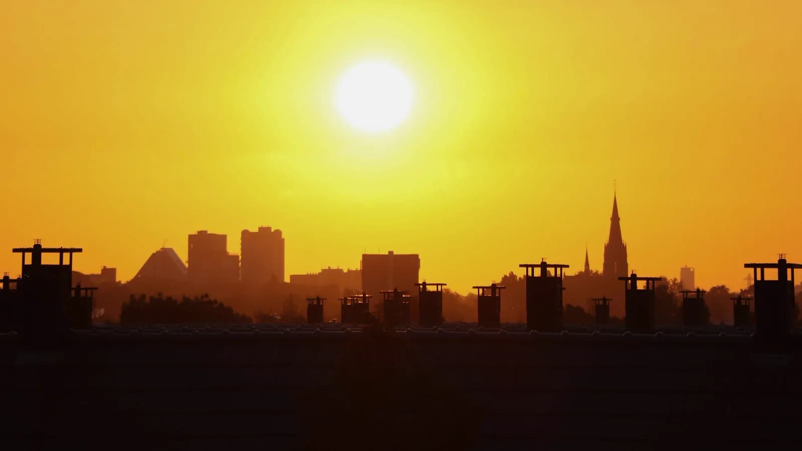 Soleil orange vif au-dessus de la silhouette d'une ville pendant un épisode de forte chaleur